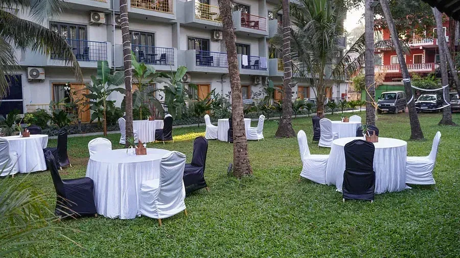 An open-air banquet space in the lawn with comfortable chairs around tables at Indie Stays Resort, Goa.