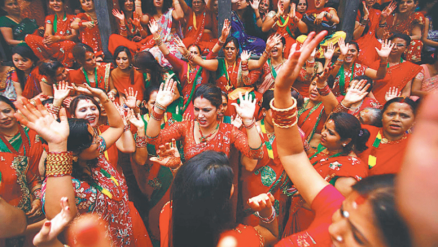 Nepalese Hindu women dressed in vibrant red sarees dancing joyfully during the holy Teej festival celebrations in Bhaktapur, Nepal.