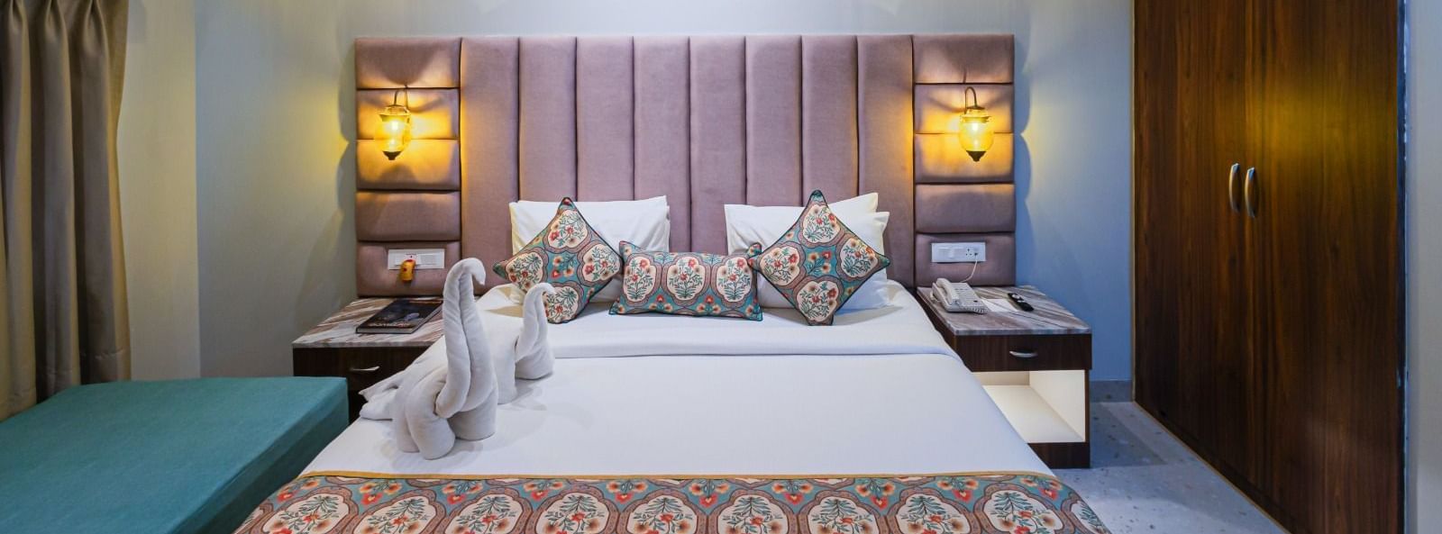 Double bed at Bamboo Saa Resort & Spa, Udaipur with upholstered headboard and towel figurines.