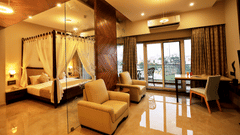 Overview of the Suite Room with a king bed, single seater sofas next to a marble wall - VITS Devbhumi, Dwarka