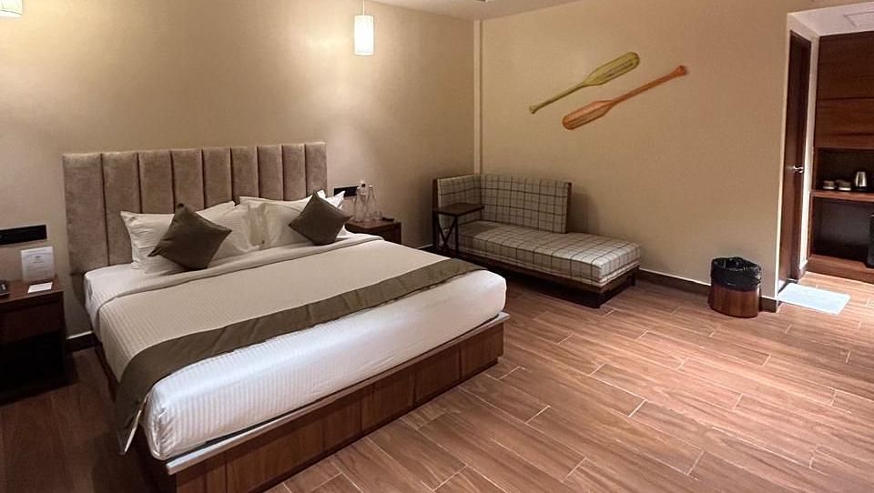 A side angle shot of a room that has wooden flooring and ceiling with a king size bed and a cosy sofa A wide angle shot of a room with wooden flooring and a king size bed with a side table | Arina Island Resort 