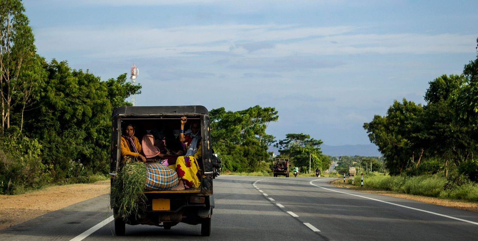 people-traveling-back-crammed-vehicle-down-road-india