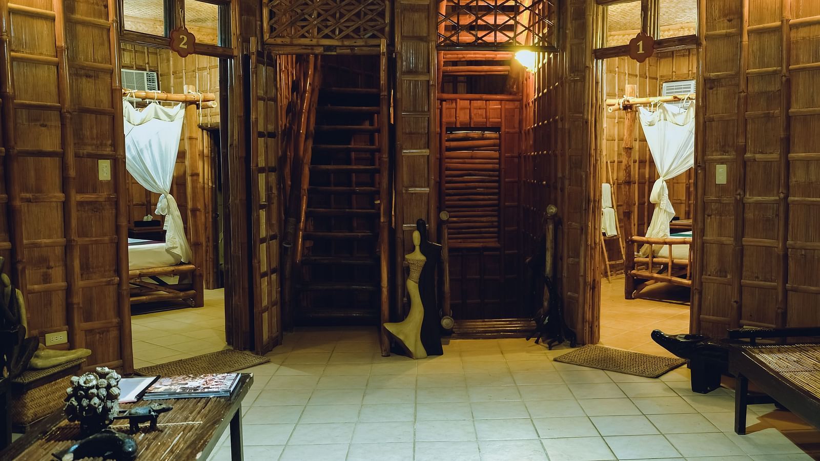 Seating area at Flower Island Resort featuring bamboo panelling around the room, warm lighting and giving a glimpse of the bedrooms.
