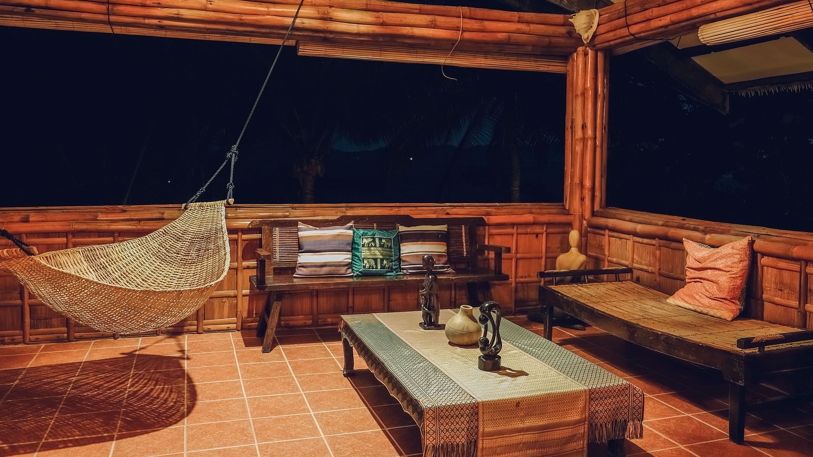 Sitting area at Flower Island Resort featuring a cosy setting with wooden seating area, a hammock, and warm lighting.