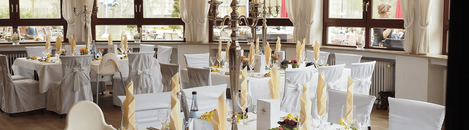 Image of a banquet hall with cutleries and napkins placed in the glasses. 