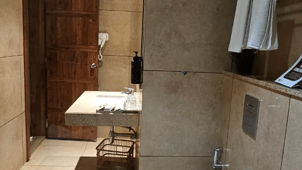 Tiled bathroom with toilet and washbasin counter at Cholaa Dynasty, Kumbakonam.