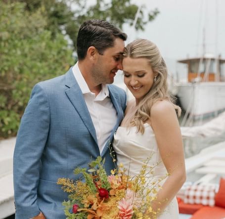 Bride and groom standing close, smiling and holding a vibrant bouquet of flowers at Casa Morada.