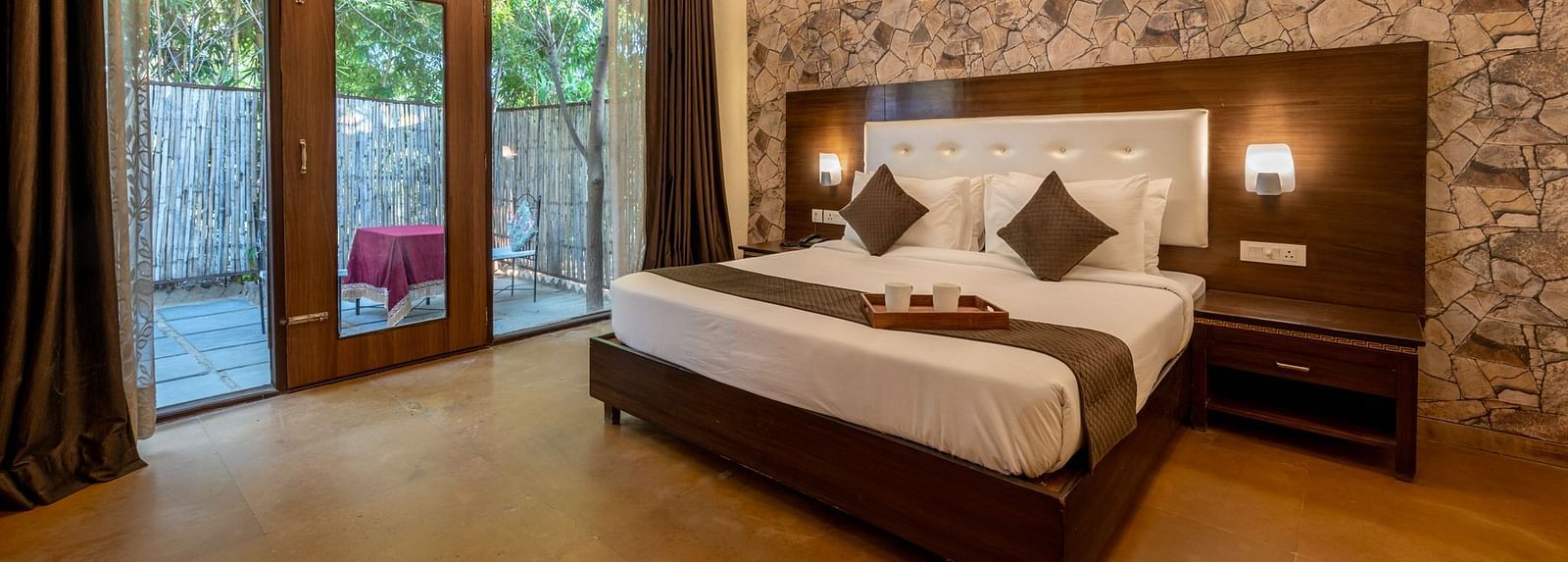 A room with a bed, lamps on the headboard, a ceiling fan, large glass doors with curtains at Valley by Grassfield 