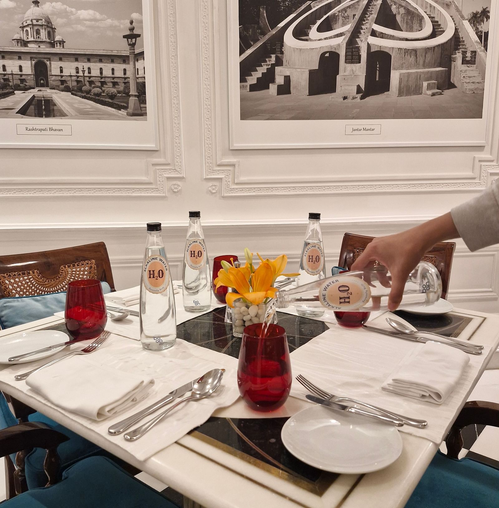 An image of a table setup with alkaline water being poured from a bottle into a glass - Claridges Collection