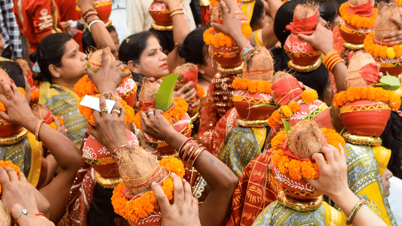A colourful and festive gathering of women in traditional attire, carrying decorated earthen pots topped with a coconut.