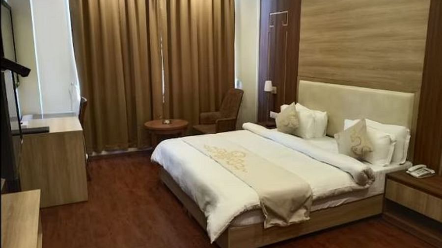 A queen bed with cushioned headboard and side tables inside Premium Room at Sumitel Gangtok