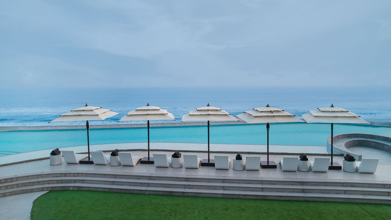 Swimming Pool at Swosti Premium Beach Resorts in Puri under a cloudy sky featuring pool deck and an infinite view of the sea appearing to be almost blended with the sky