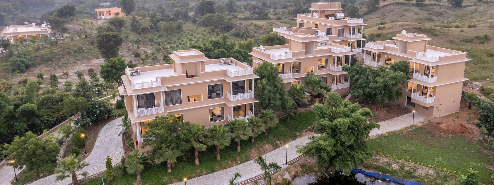 An aerial image of our building with the reflection of the trees surrounding it in the nearby water body - Rajbagh Wellness, Udaipur