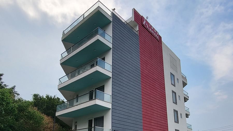 A facade of Inde Hotel Golf Course Extension featuring multiple storeys and balconies on each floor, and cars parked on the lawn