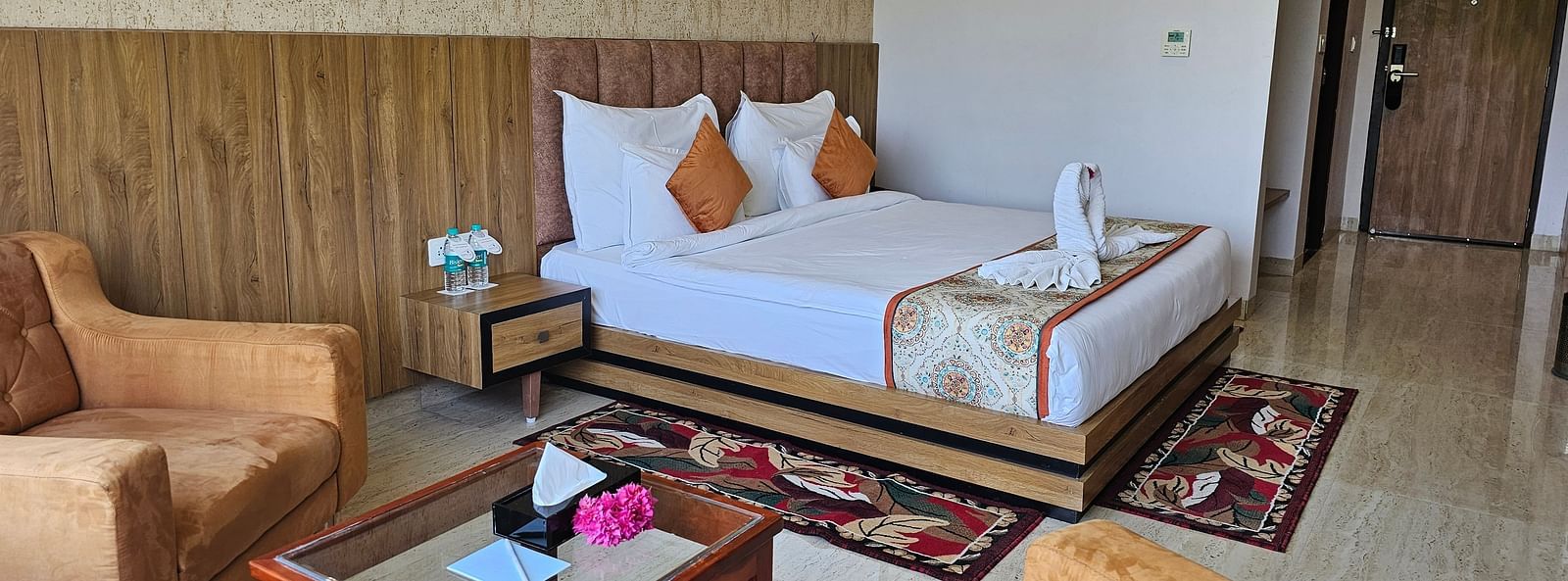 An interior shot of a hotel room at Bamboo Saa Mulberry Resort, with a bed, seating area, and a decorative rug.