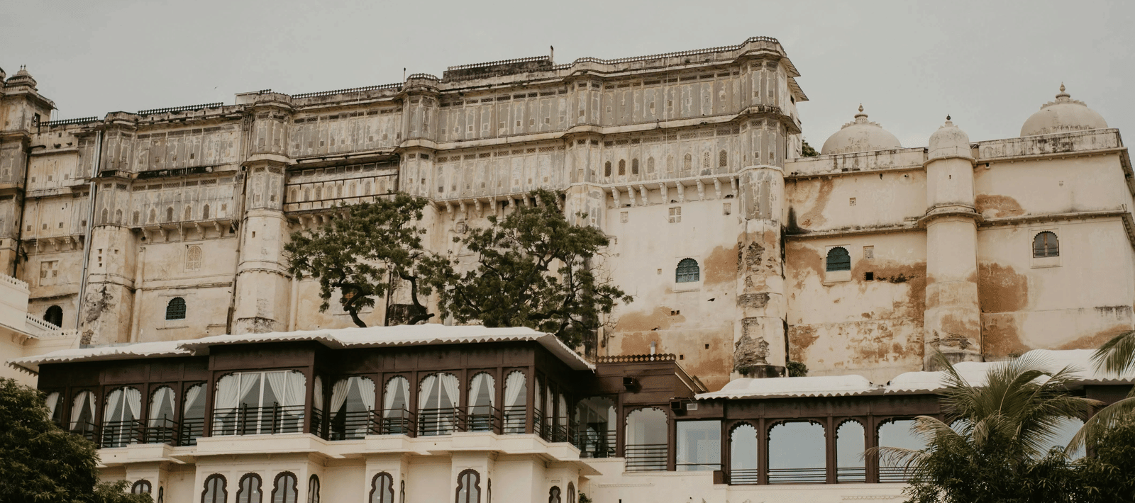 Facade of the majestic City Palace of Udaipur featuring several windows and and intricate columns made on the exterior.