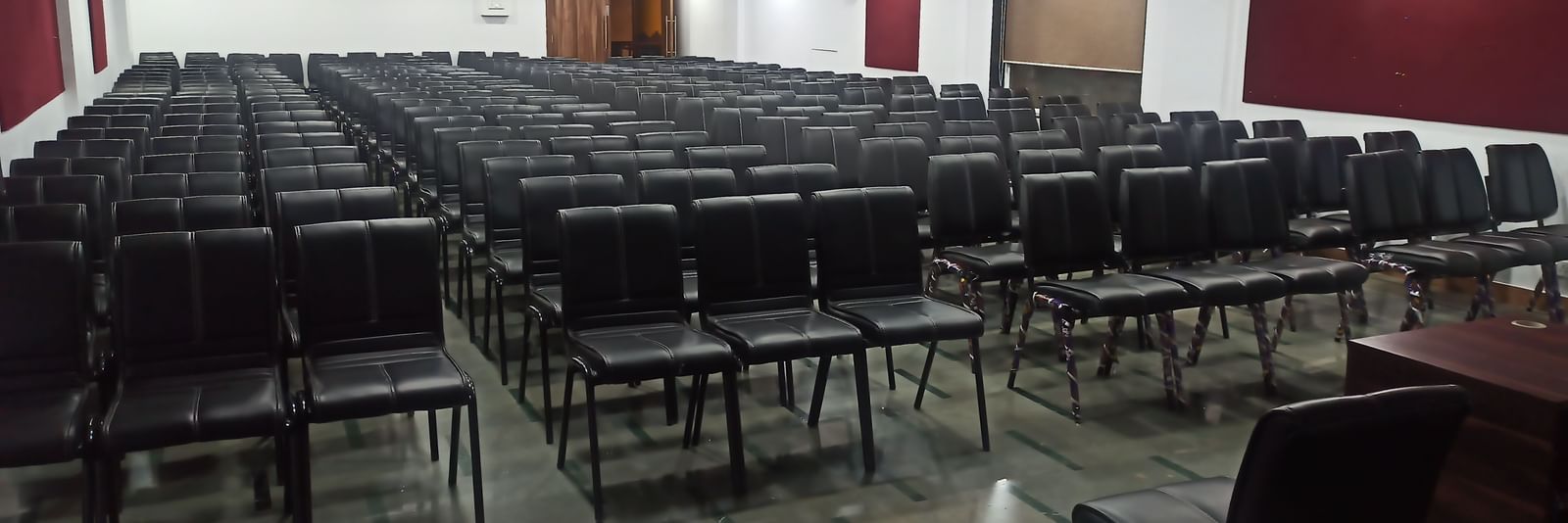 Theatre style seating arrangement with rows of black chairs in a rectangular hall at Mayur Retreat.