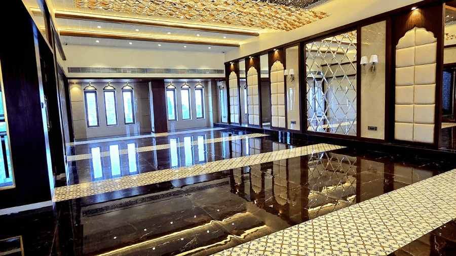 Long banquet corridor with reflective flooring and ceiling lights at Hotel Mumbai House, Digha, Airoli.