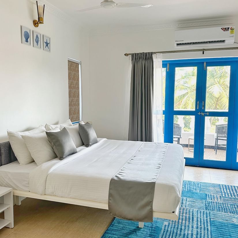 A king bed with blue door to the balcony inside one of the rooms at Azalea By Stone Wood Premier, Orlim