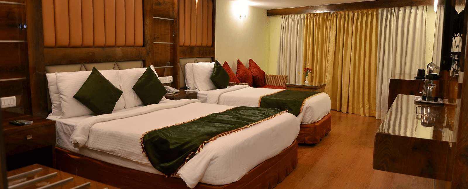 A large family room with two double beds, wooden furniture, and vibrant green cushions - Benzz Park, Kodaikanal