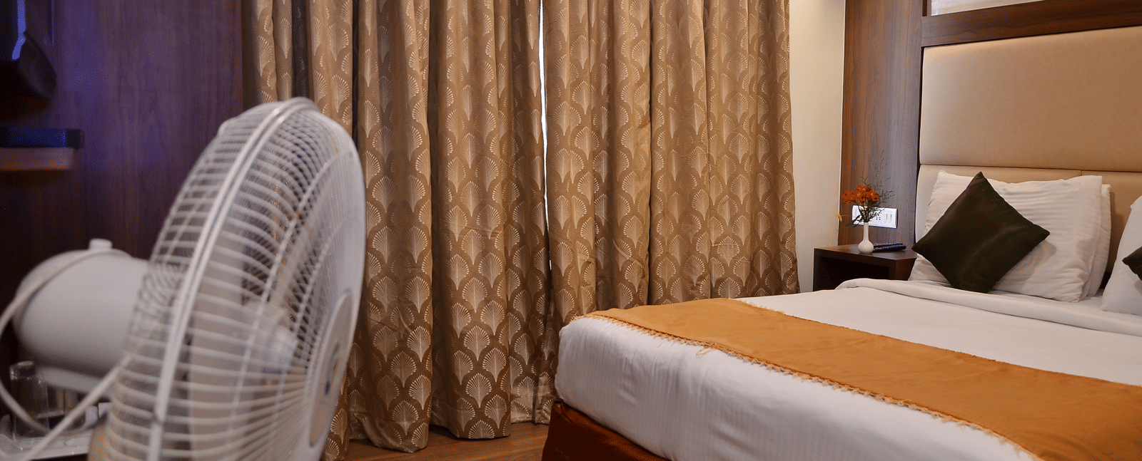 A neatly designed room with a single bed, curtain backdrop, and pedestal fan for added comfort - Benzz Park, Kodaikanal