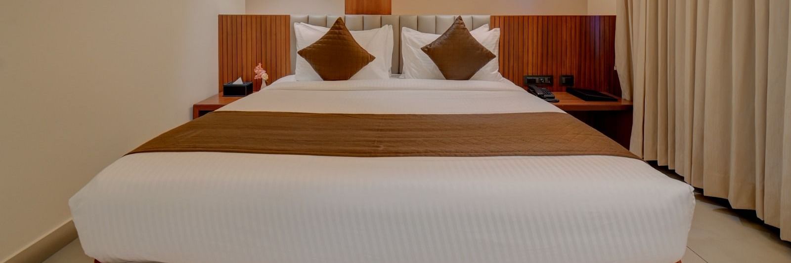 An image of a room at Hari Govindas, Siddappa Square, featuring a bed with a window on the side.