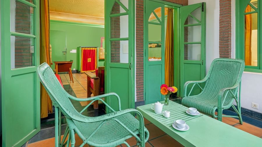 Two chairs and a coffee table with cups on them in the balcony of one of the rooms | Mango Hill, Pondicherry