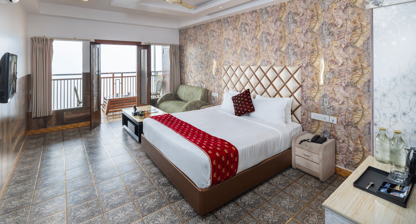 The interior of the Premium Club Suite at Parakkat Nature Hotel and Resorts, Munnar, featuring a large bed, a stone-patterned accent wall, a seating area, and sliding doors to the balcony.