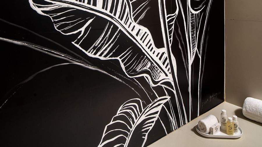 A painting on the wall of the leaves in our hotel bathroom with towels by the side of the wall - S Hotel Montego Bay, Jamaica