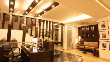 Reception lobby at Emblem Hotel, New Friends Colony, New Delhi featuring a desk with computer and telephone, and opposite to it there is a sofa seat for the guests.
