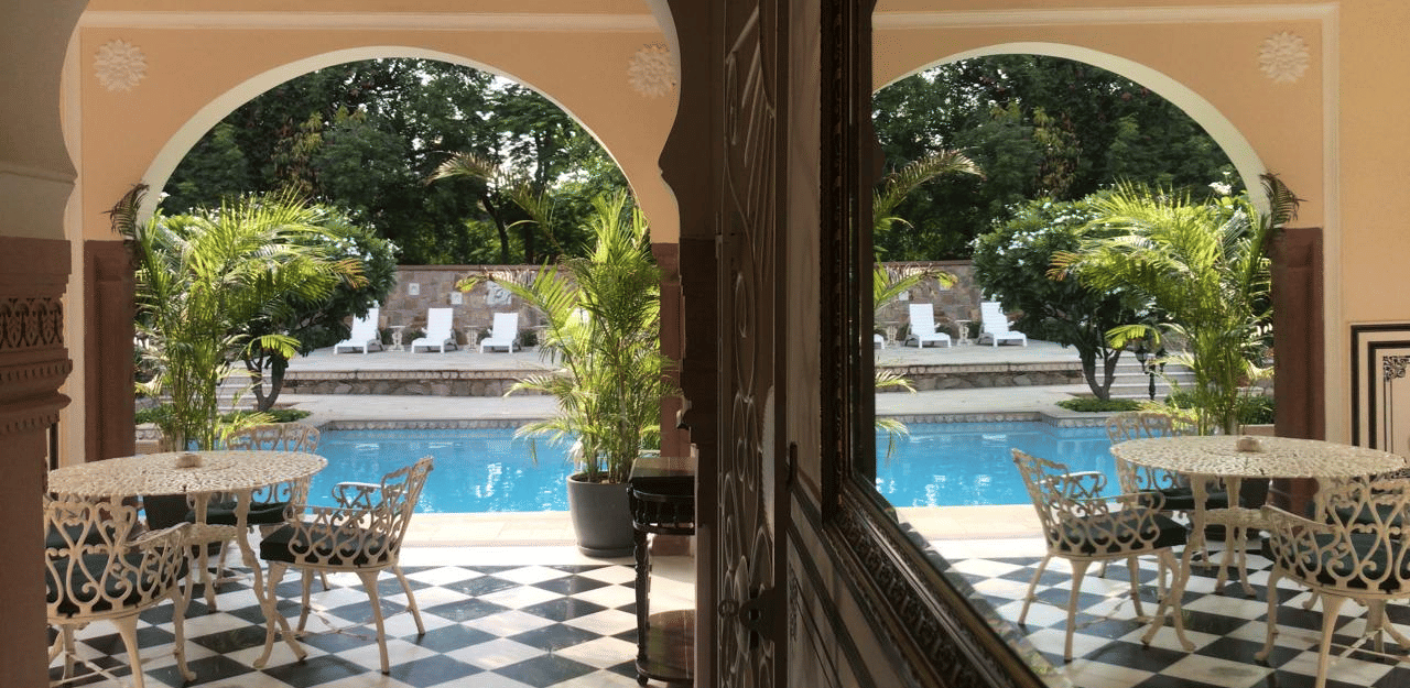A beautiful view of the elegant poolside area through classic arches and tall pillars - Khas Bagh, Jaipur.
