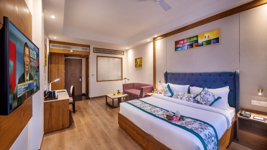 Club room featuring a large bed with a blue padded headboard, desk, and stylish decor.