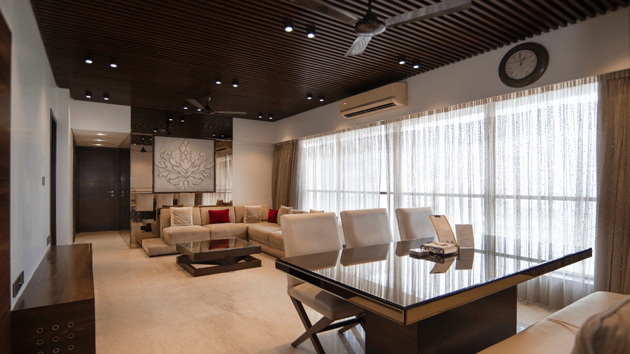 Dining and living area at Theory9 - Premium Serviced Apts, Khar, with a glass-top table, cream chairs, and large windows with sheer curtains.