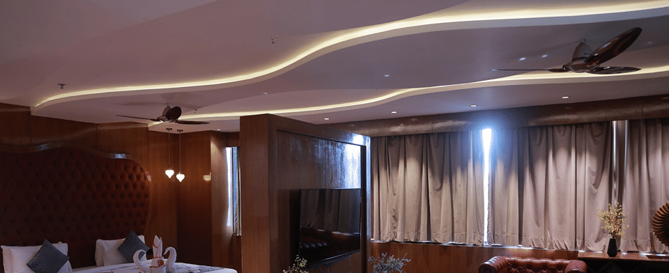 Sky Suite bedroom and lounge with a bed, wall-mounted television and red leather sofas under a curved ceiling
