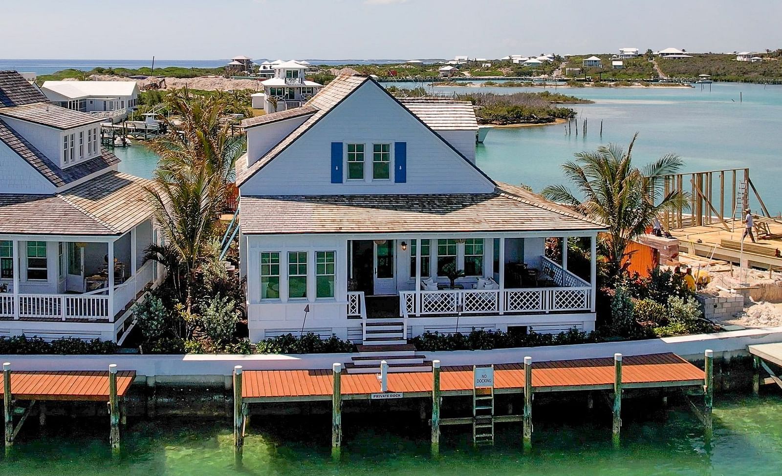 Waterfront cottages built on stilts over turquoise waters, surrounded by lush greenery and palm trees | Abaco Inn