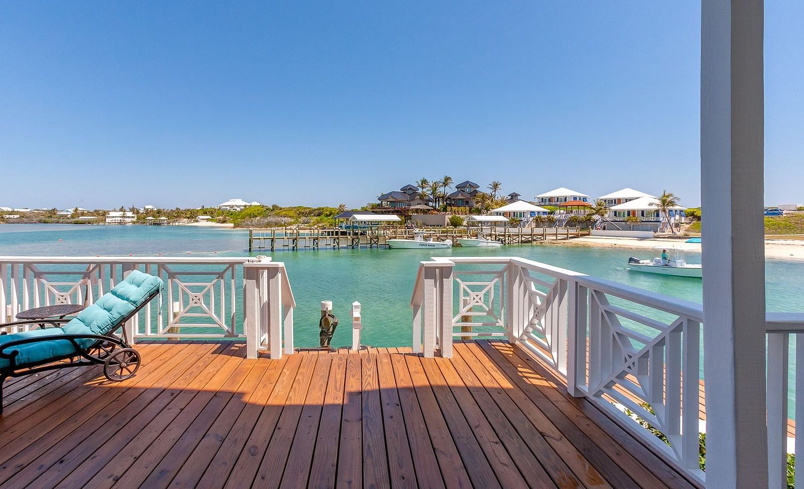 Wooden deck with blue sun loungers overlooking the water and nearby houses | Abaco Inn