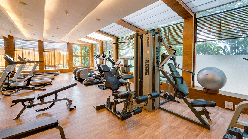 An interior view of Pulse Gym with numerous gym equipment items, a floor to ceiling window on all sides and premium lighting on the ceiling at at Pulse Gym inside Kenilworth Hotel, Kolkata.