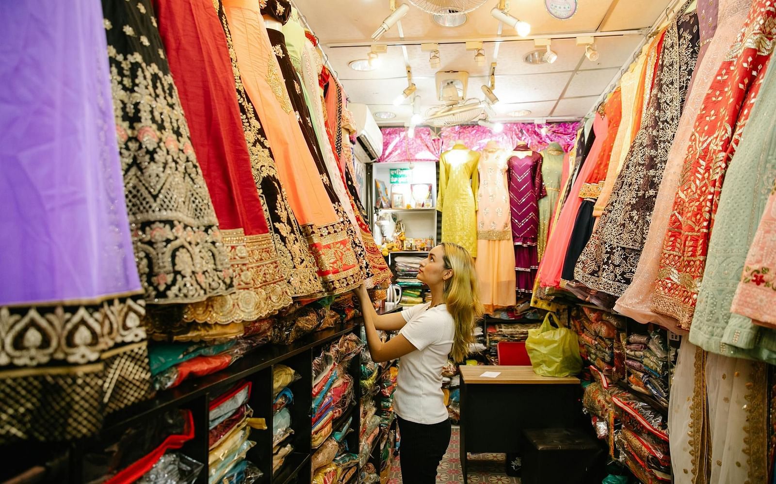 Image of clothes hanging fron the celiling and a person looking at the clothes.