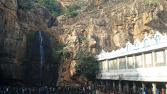 An overview of the Kapila Theertham Temple, carved into the rocky base of the Tirumala Hills, stands beside a sacred waterfall.