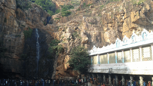 An overview of the Kapila Theertham Temple, carved into the rocky base of the Tirumala Hills, stands beside a sacred waterfall.