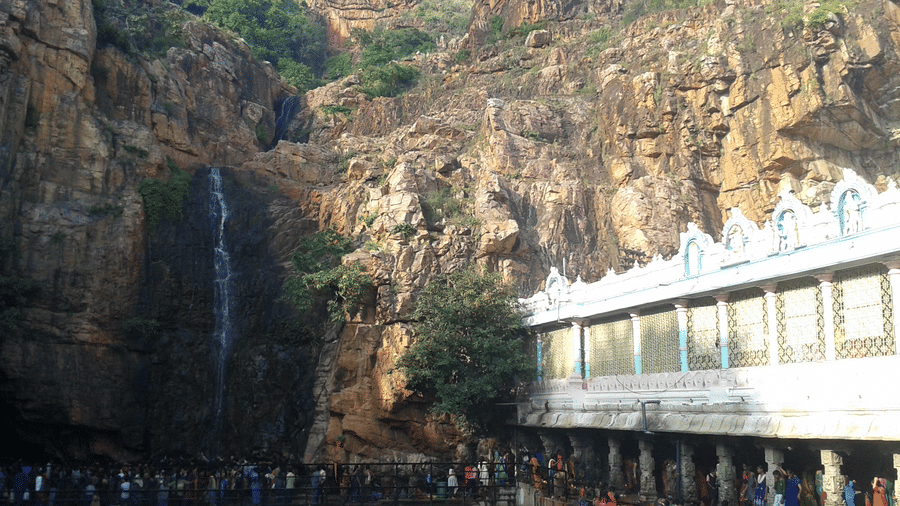 An overview of the Kapila Theertham Temple, carved into the rocky base of the Tirumala Hills, stands beside a sacred waterfall.