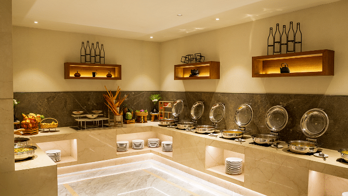 A corner view of the buffet area at The Residency Tower, Chennai, showcasing a variety of different cuisines artfully arranged.