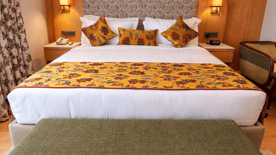A room at Mountnoor Sarovar Premiere, Pahalgam, with a large bed, bedspreads, pillows, lamps and a table.