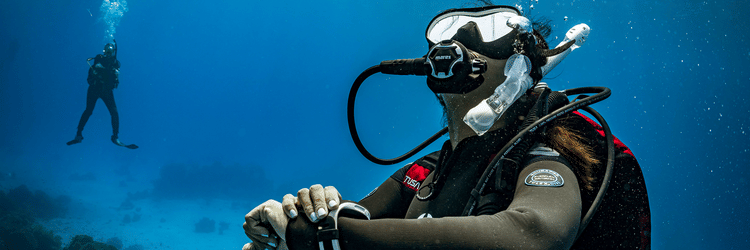 Barefoot Scuba Resort | Diver navigating underwater with equipment, observing marine life.