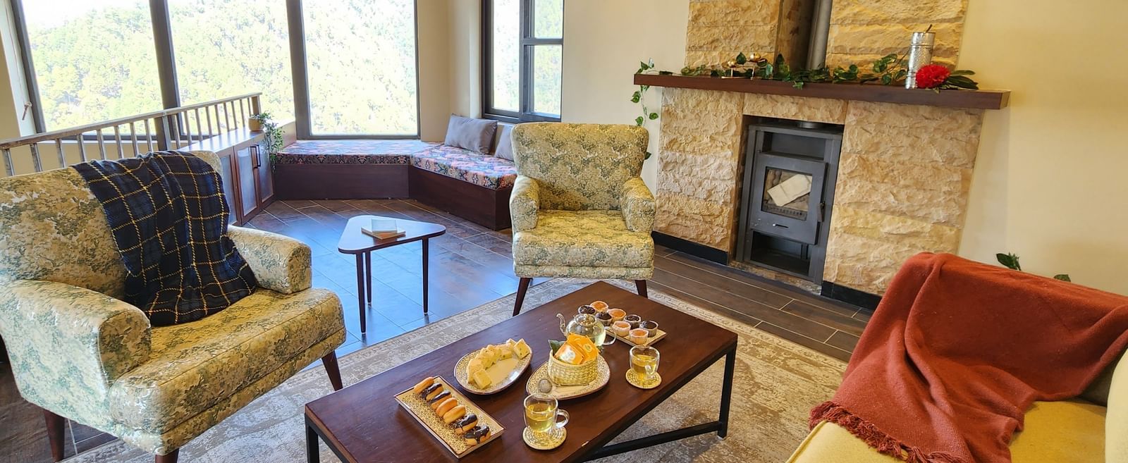 Living area with armchairs, fireplace, and wide windows at The Chamomile Estate.