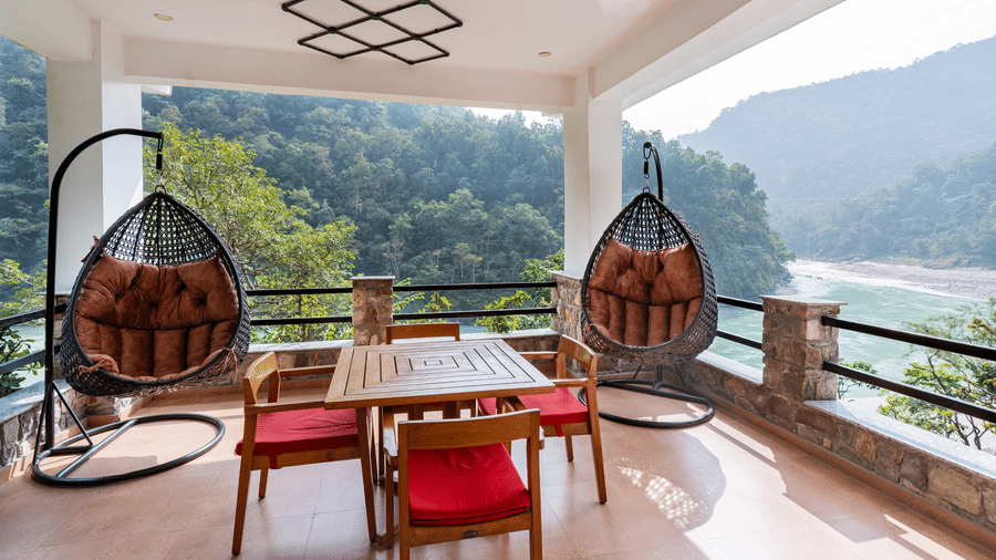 A private terrace featuring 2 hanging swing chairs and a 4-seater centre table with 4 chairs, overlooking a river | Summit by the Ganges Beach Resort & Spa, Rishikesh