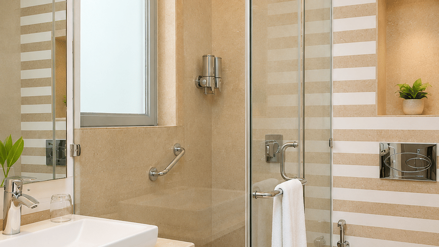 Hotel bathroom with a glass-enclosed shower, a countertop basin, a Western-style toilet and patterned tiled flooring throughout the room.