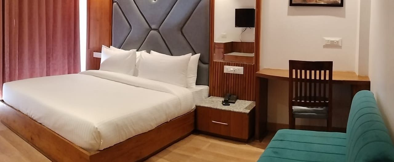 A sofa in front of a bed  in Premium Room With Balcony at DLS Ark Holiday Inn, Banikhet.
