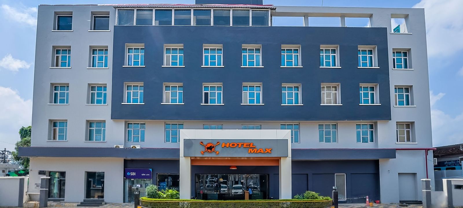 A front view of a hotel building with the name of the hotel mentioned on a signage - Max Hotel Prayagraj