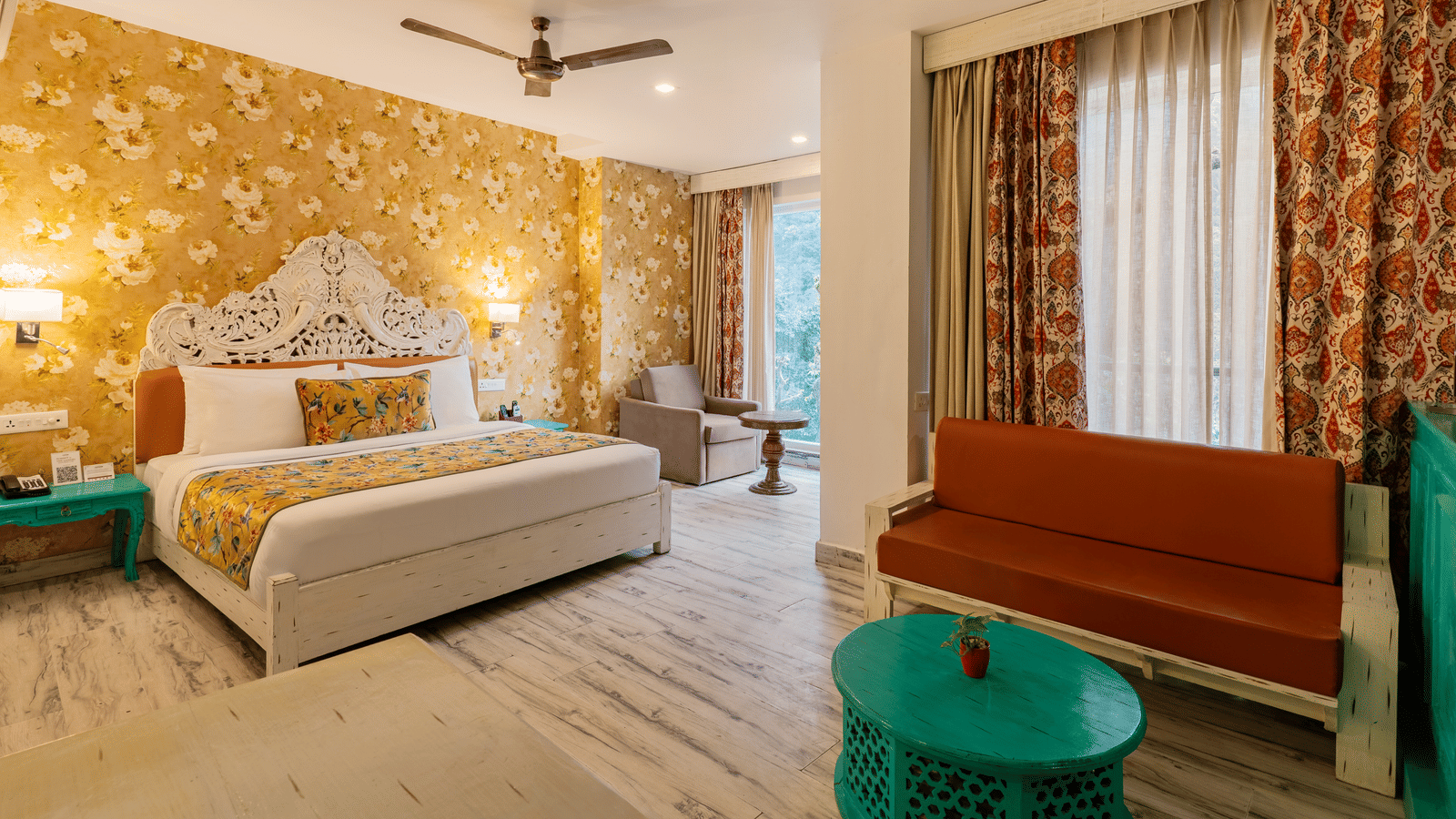 A well-lit suite featuring brightly coloured furniture, an accent wall, full length curtains, and an attached balcony | Summit by the Ganges Beach Resort & Spa, Rishikesh